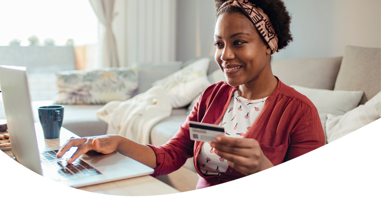 young woman holding credit card and working on laptop