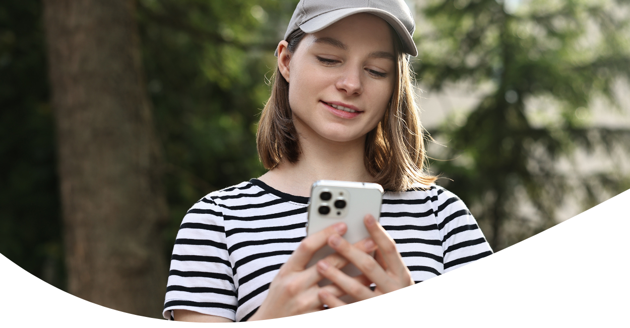 Woman in ball cap looking at smartphone