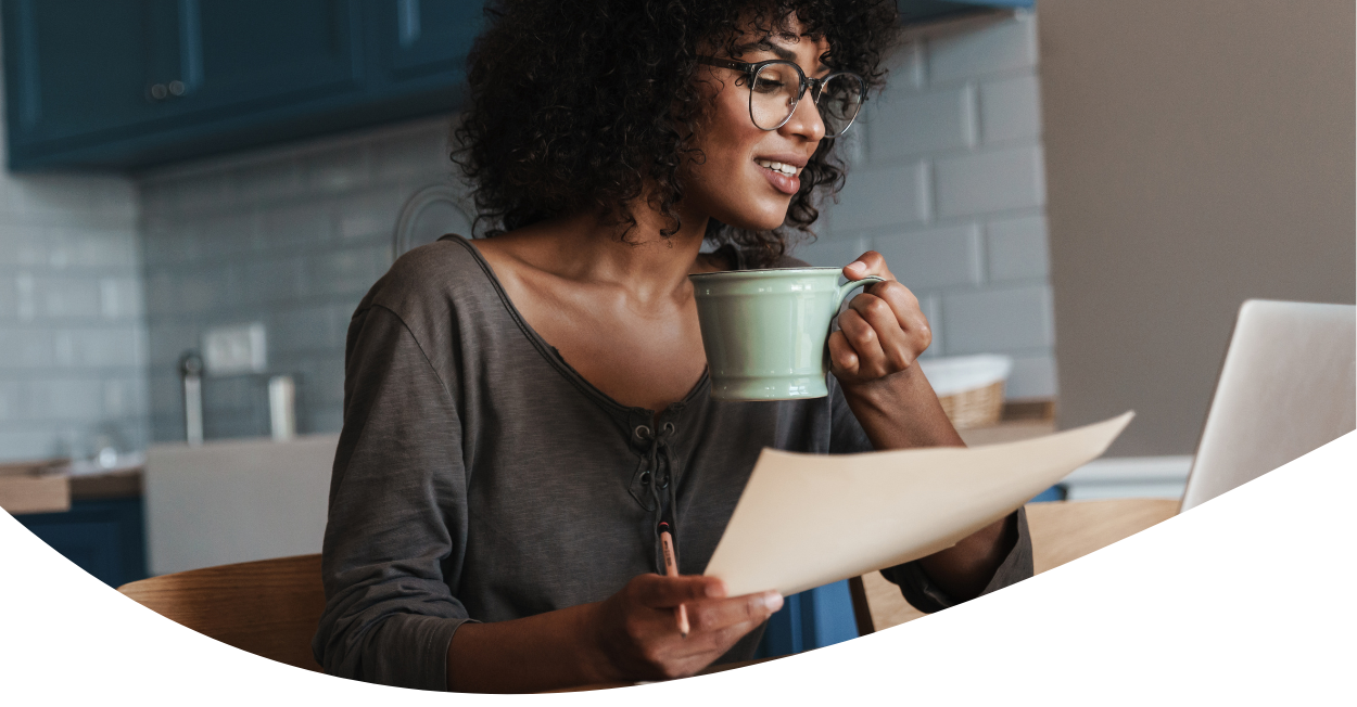 woman holding a coffee and working on laptop