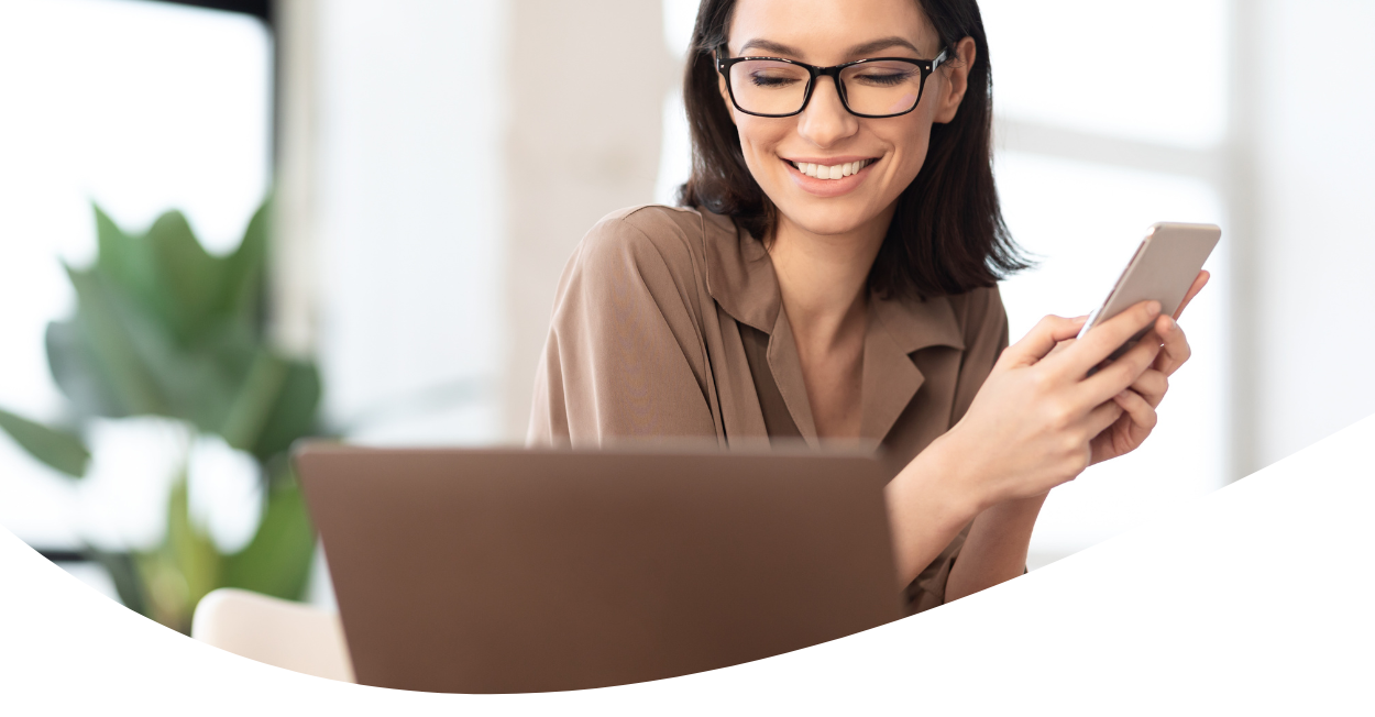 woman working on laptop and holding cellphone