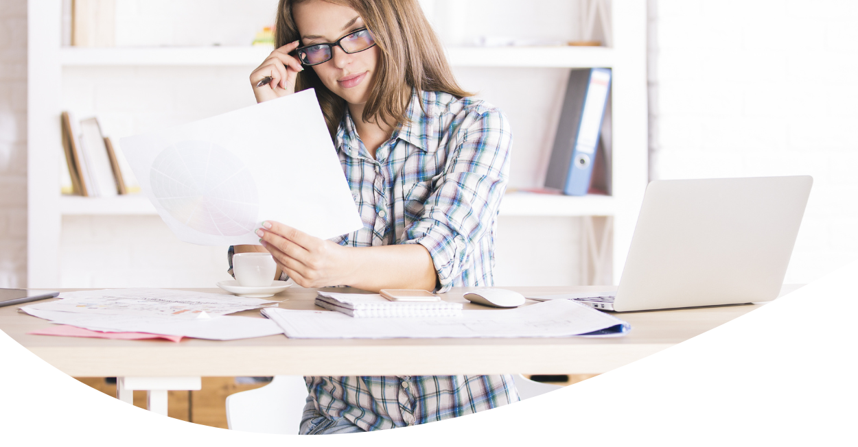 woman working on laptop and holding papers