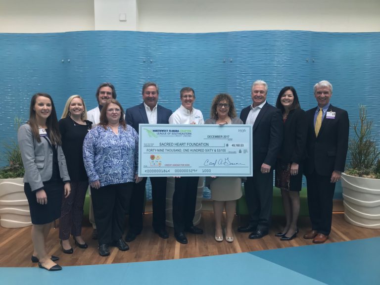 NWF Chapter of the LSCU members with Sacred Heart staff holding donation check