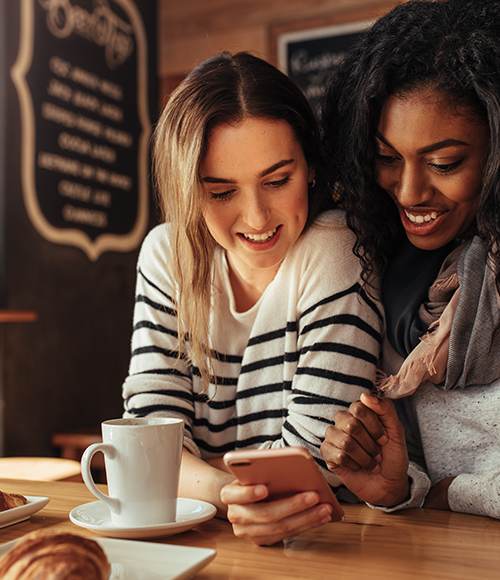 Friends looking at cell phone in cafe