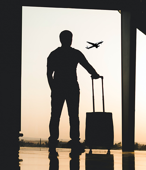 Silhouette of man looking out airport window at airplane