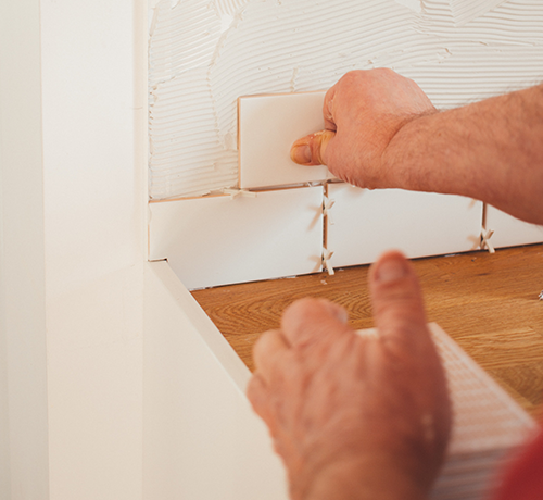 person installing tile backsplash