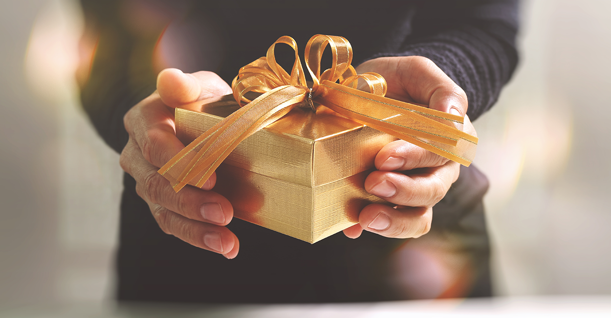 person holding out present with gold wrapping